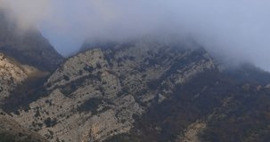fog and sun on the top of the cliff. mountain peak in mist and light. dramatic view. atmospheric video. High quality 4k footage