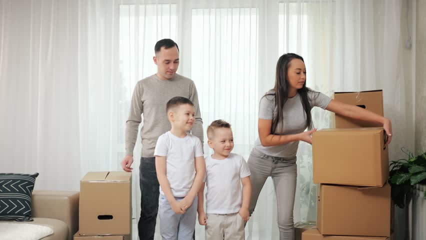 Children want to help parents carry boxes in new apartment. Boy kids enjoy helping parents with moving into new house and carrying packages | Shutterstock HD Video #1098701153