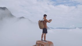 Asian Hiker Male Standing On The Rock And Using Smartphone Taking Photo Of The Top View Foggy Mountain
