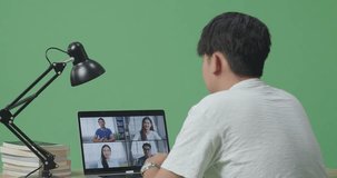 Close Up Back View Of Young Asian Male Waving Hand For Greeting And Speaking While Studying On Zoom By A Laptop On Green Screen Background At Home

