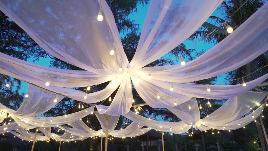 Hanging light bulb Wedding decorations under the coconut tree in the nights. Wedding event on sunset at Hawaii beach. Romantic wedding dinner.