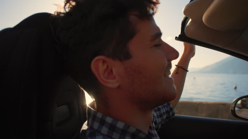 Careless relaxed man in sunglasses driving cabriolet car at fantastic golden sunset. Sun flare. Concept of success, tourism, rental cars. Happy smiling tourist travel in California. Summer vacation Royalty-Free Stock Footage #1098720795