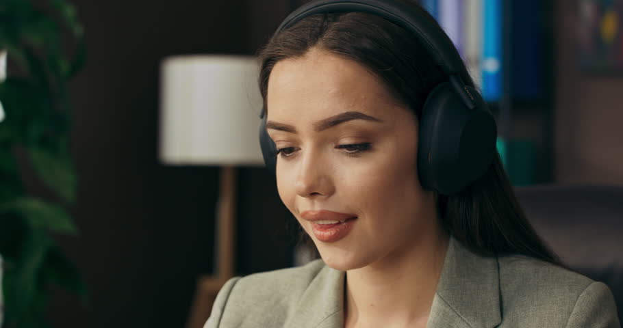Relaxed calm woman sitting at table relaxing listening to music wearing wireless headphones talking nline dream job work . | Shutterstock HD Video #1098721431