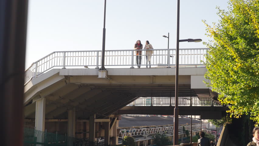 4K Happy Asian woman friends walking on overpass bridge for crossing city street together in Tokyo city, Japan in the morning. Attractive girl enjoy and fun outdoor lifestyle travel on winter vacation