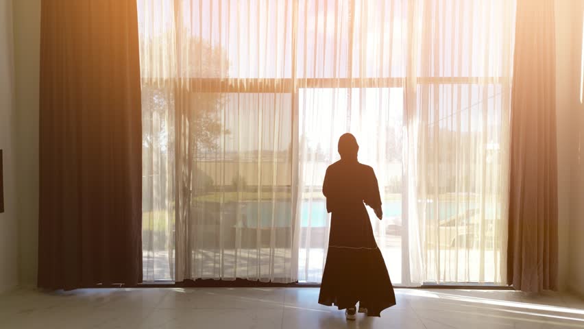 Woman in black dress opens curtains at luxury villa | Shutterstock HD Video #1098724873