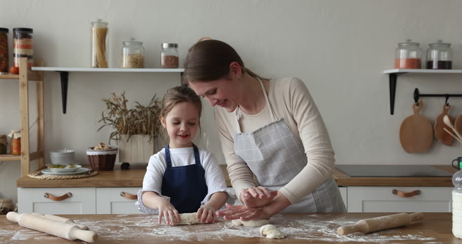 Loving mother teach little pretty daughter to cook, preparing together pastry family recipe, kneading dough with hands, enjoy communication and cooking process in modern cozy kitchen. Lifestyle, hobby Royalty-Free Stock Footage #1098725779