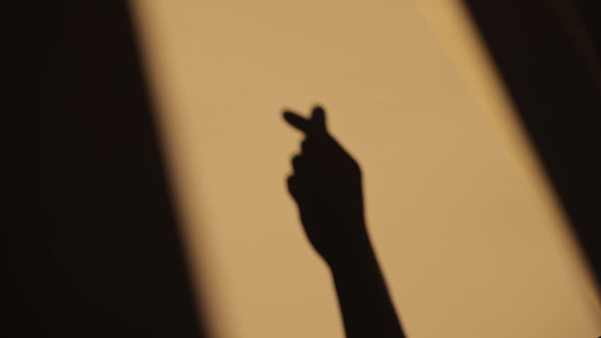 silhouette of human hands making korean heart sign shadow on a white backgroun