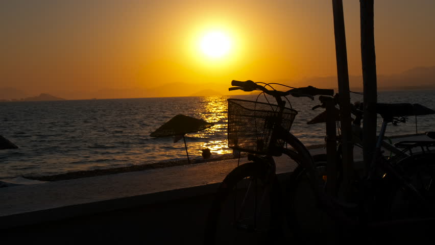 Cycling hobby silhouette on island. A view of abandoned bike on the sandy shore during nightfall. A concept of sporty life by the sea. Royalty-Free Stock Footage #1098729733