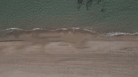 Aerial view video top-down beach on sea. Nature video view of beautiful mediterranean beach and sea at sundown. Drone footage top down view flying Downward.