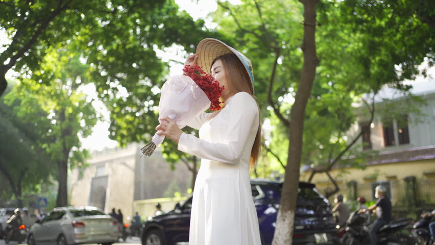 Portrait of Asian with bouquet flowers, Vietnamese woman girl traveling in Hanoi urban city town, Vietnam. People lifestyle.