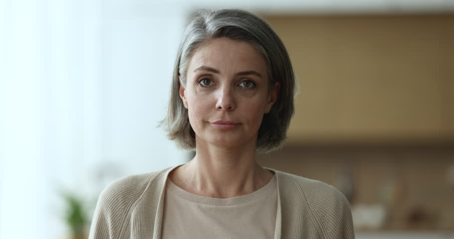 Head shot of pretty middle-aged 45s woman with grey hair and casual clothes standing alone in domestic room. Mature female with attractive appearance posing at home, older generation person portrait Royalty-Free Stock Footage #1098732517