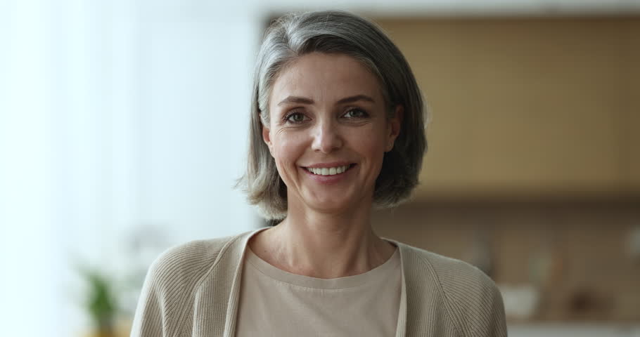 Head shot of pretty middle-aged 45s woman with grey hair and casual clothes standing alone in domestic room. Mature female with attractive appearance posing at home, older generation person portrait | Shutterstock HD Video #1098732517