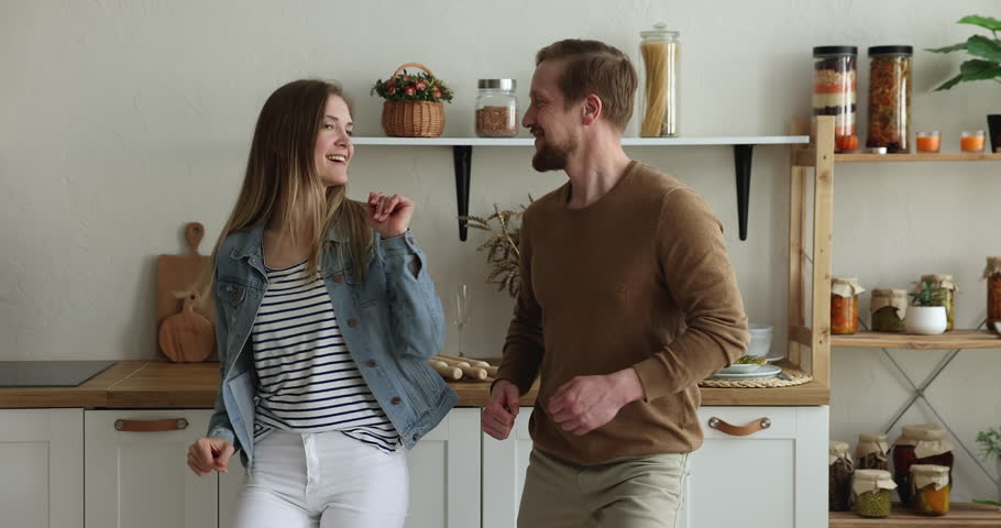 Happy married millennial couple holding hands and dancing together in the kitchen, celebrate life event, having festive mood enjoy favourite song spend weekend pastime at modern cozy home. Love, hobby | Shutterstock HD Video #1098732539