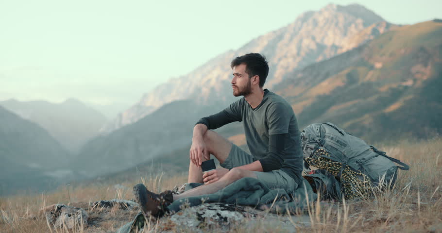 lonesome climber sitting on top of mountain, drinking coffee in thermos. adventurer relaxing after achieving a goal. zen, freedom concept 4k Royalty-Free Stock Footage #1098733115