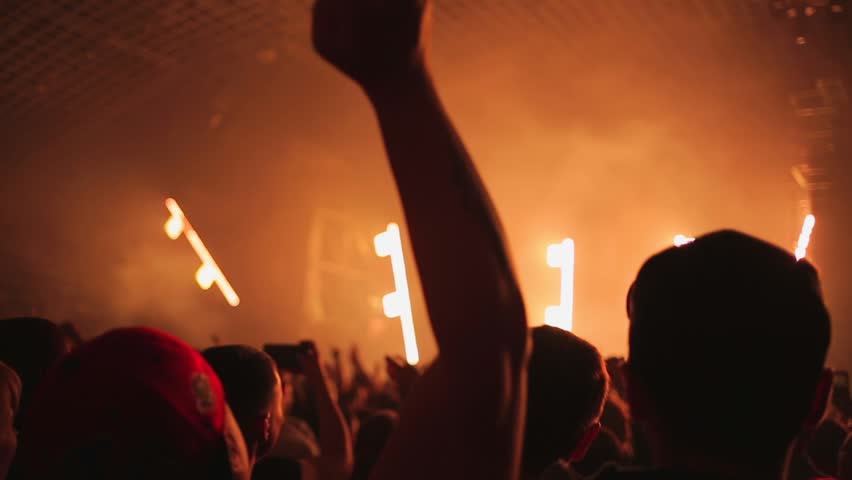 People at a musical rock concert cheerfully dance and wave their heads in time with the music. Club atmosphere, rays of multicolored light. Rear view. The concept of entertainment. | Shutterstock HD Video #1098733473
