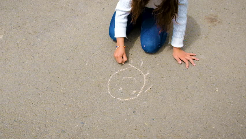 The child draws with chalk on the pavement. Selective focus. | Shutterstock HD Video #1098736941