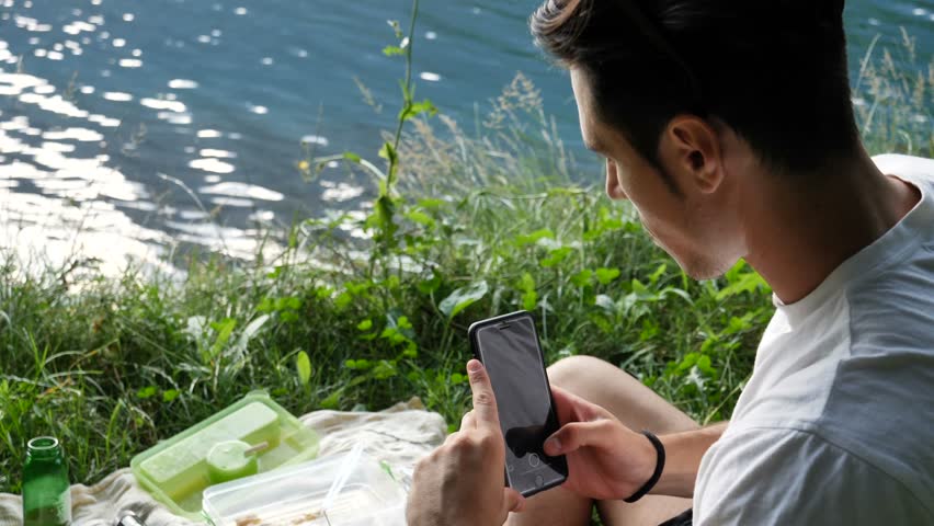 Young man taking photograph of food at picnic in nature