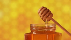 Close up view of this healthy food made by bees in nature, acacia tree honey filmed in 4k video against honeycomb yellow background. Getting honey from a jar with a wood dipper.