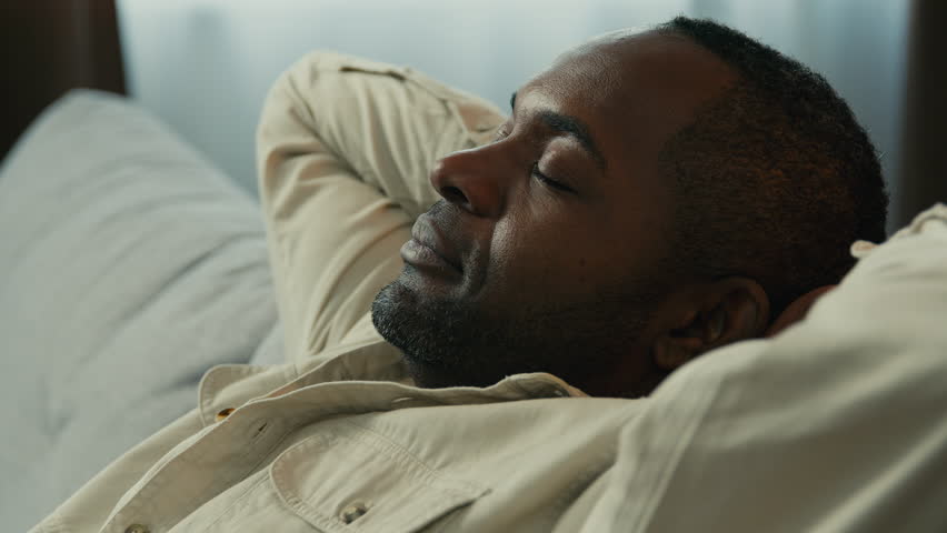 Headshot calm relaxed happy african american man relax resting on couch enjoying calmness sleepy lazy male dreamer dozing on comfortable sofa in living room lies with eyes closed dreaming meditating