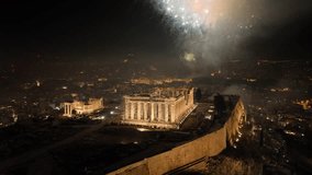 Aerial drone closeup night video of illuminated Acropolis hill and the Parthenon during New Year's eve 2022 with beautiful fireworks exploding, Athens historic centre, Attica, Greece