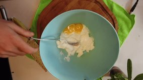 Breaking egg and placing into dish with cream. Stearing together. Overhead, slow motion. High quality 4k footage