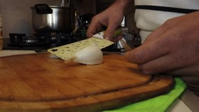 Hand smashing garlic with a kitchen cleaver on the chopping board. Slow motion. High quality 4k footage