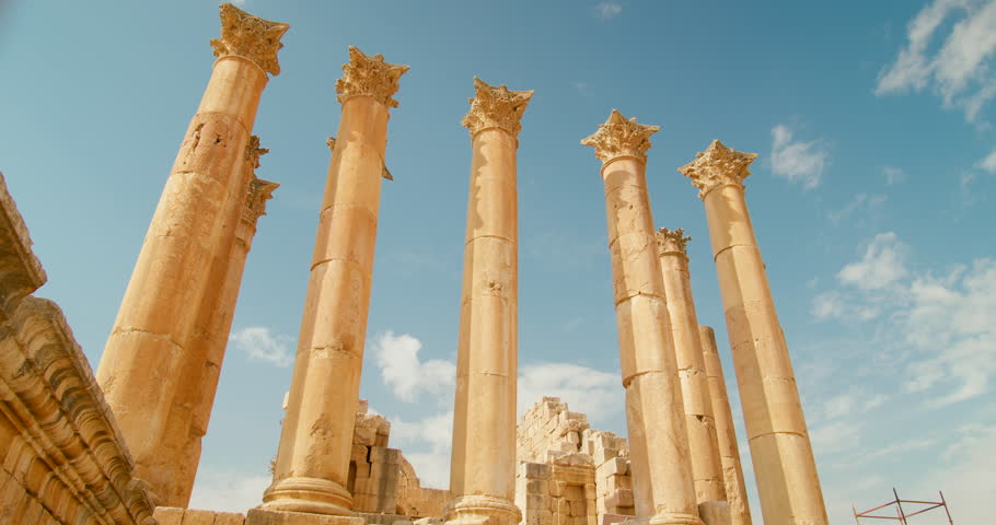 Bottom view of row of columns in Temple of Artemis in Jerash, Jordan. Ruins of pillars placed together and established as ancient architecture with sunny sky in background. 4k panning shot  Royalty-Free Stock Footage #1098748537