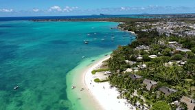 Mauritius - aerial video landscape view along the coastline at Troy aux Biches Beach and Mont Choisy Beach, with people walking on beach and boats swimming in the water of Indian Ocean, video footage 