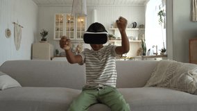 Little enthusiastic African American boy use VR helmet for video games sits on sofa driving invisible car. Young carefree teenager with virtual reality headset on head enjoys games with AR effect - Powered by Shutterstock - Get 15% off with code: PIKWIZARD15