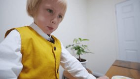 Portrait of focused 5 years old caucasian boy in stylish bright waistcoat tie bow playing computer game at the laptop. A boy is busy playing online and looking at the screen