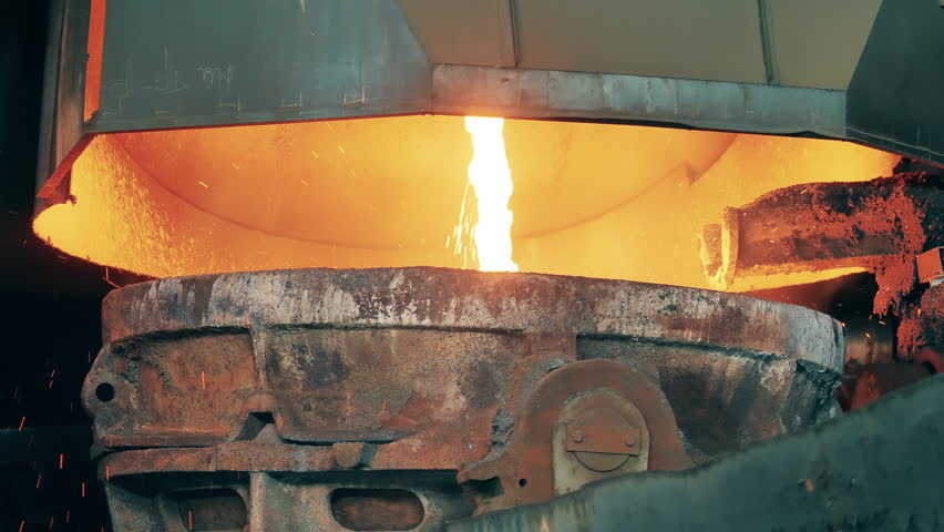 Metallurgical factory equipment, metallurgy industry concept. Melting furnace with molten metal flowing out of it | Shutterstock HD Video #1098753359