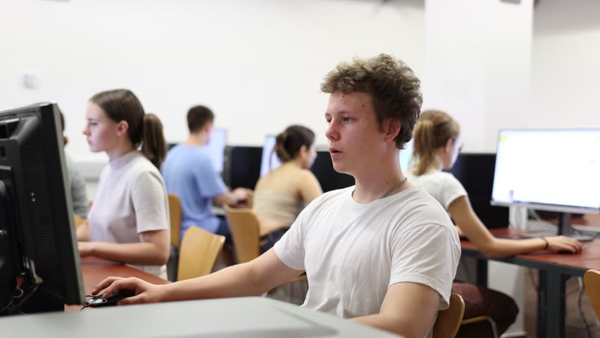 Clever focused male teenager solving tasks of computer science in the auditory Royalty-Free Stock Footage #1098754725