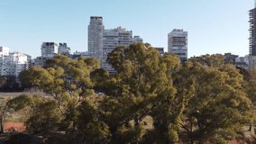 Pedestal up reveal of Palermo park and Le Parc skyscraper building in Buenos Aires capital city of Argentina with car commuter traffic. Aerial drone view