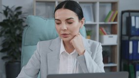Shooting of Caucasian smiling businesswoman in gray suit looking at webcam, making online business call, talking with client, distance, headshot portrait. Good-looking young woman sitting at table and - Powered by Shutterstock - Get 15% off with code: PIKWIZARD15