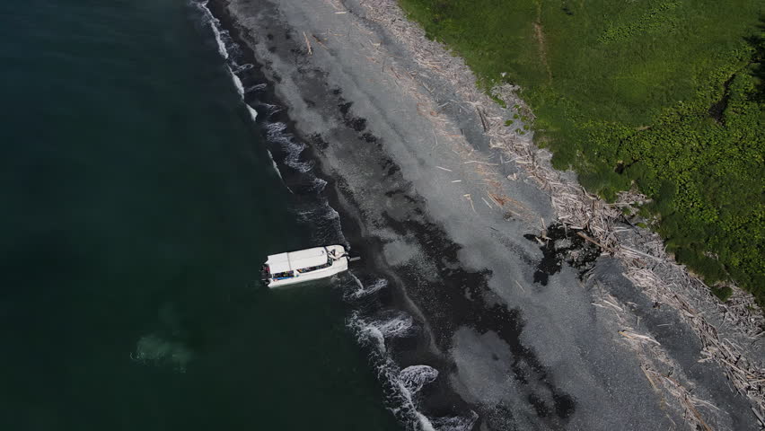 a boat is docked at the shore of a body of water. Aerial view of a small motor boat on the Black Sea coast