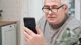 Hoary old man looking at web camera, holding phone, talking with clients partners online. Senior grandpa smiling chatting with friends, family via video call. Modern technologies and older generation.