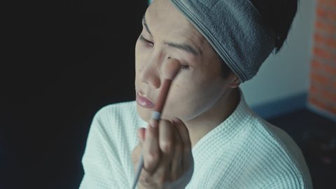 Young Asian transgender queer man doing makeup : vidéo de stock