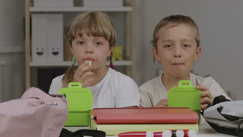 Boy and girl are eating their snacks at the table | Shutterstock HD Video #1098770331