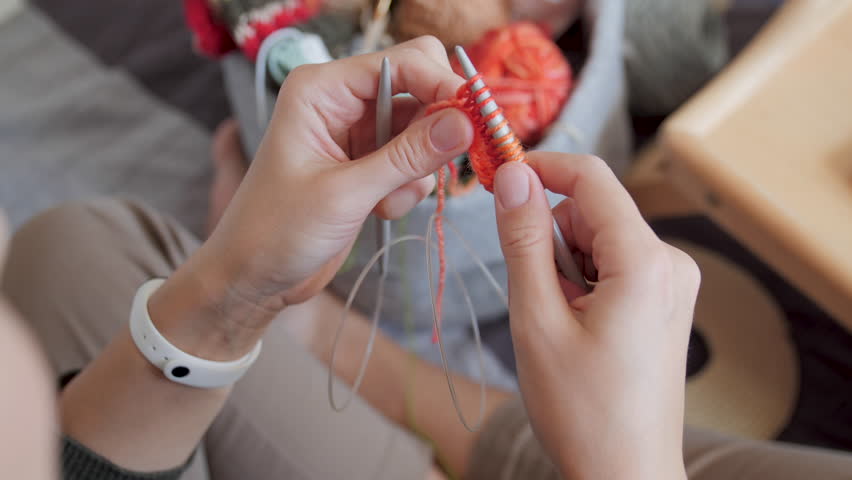 Close-up video of woman knitting something small. Anti-stress hobby. Tranquil leisure at home. Handicraft. Online lessons for amateurs on laptop.