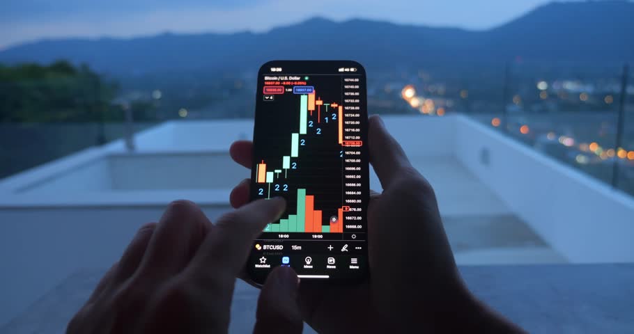 Close up male hand holding smartphone trading on crypto stock market outdoors on the roof of luxury villa. Male trader use smartphone analyze crypto growth stocks fund at evening on view of mountain. | Shutterstock HD Video #1098772449