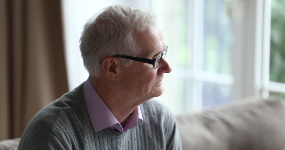 Close up face of older man in glasses sits on couch lost in sad thoughts, looks into distance, suffers from loneliness. Chronic senile disorders, life regrets, nostalgic mood, melancholy, retirement | Shutterstock HD Video #1098773567
