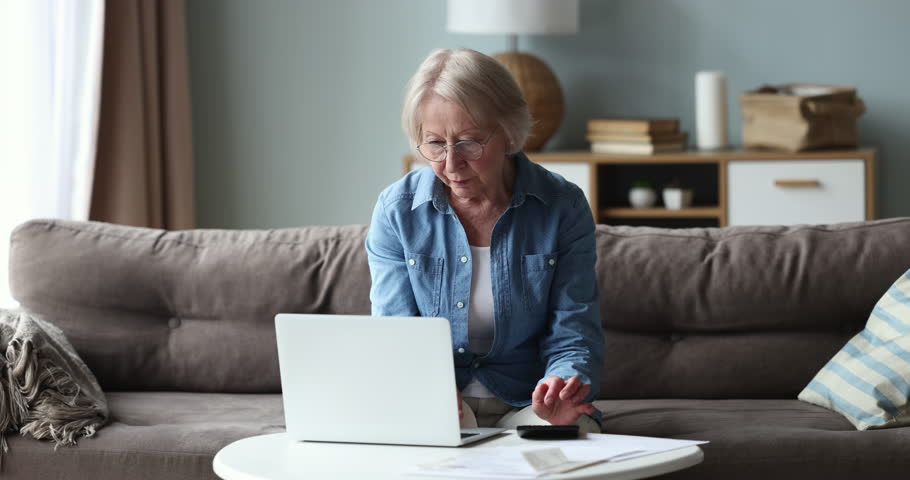 Older single woman feels stressed calculating household expenses, looks disappointed due to high electricity bills need to pay. Bankruptcy, insufficient old-age pension, huge taxes, bank debt, penalty Royalty-Free Stock Footage #1098773593