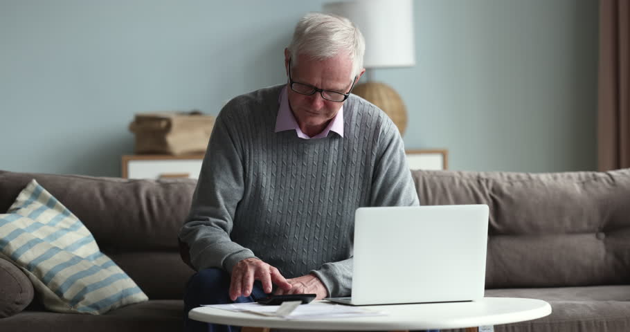 Elderly 70s single man feels desperate and stressed calculating household expenses, looks upset due to huge utilities bills need to pay. Bankruptcy, insufficient old-age pension, high taxes, bank debt Royalty-Free Stock Footage #1098773597