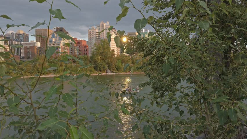 Boat on Bow river in city with skyscrapers sunset Calgary Alberta Canada