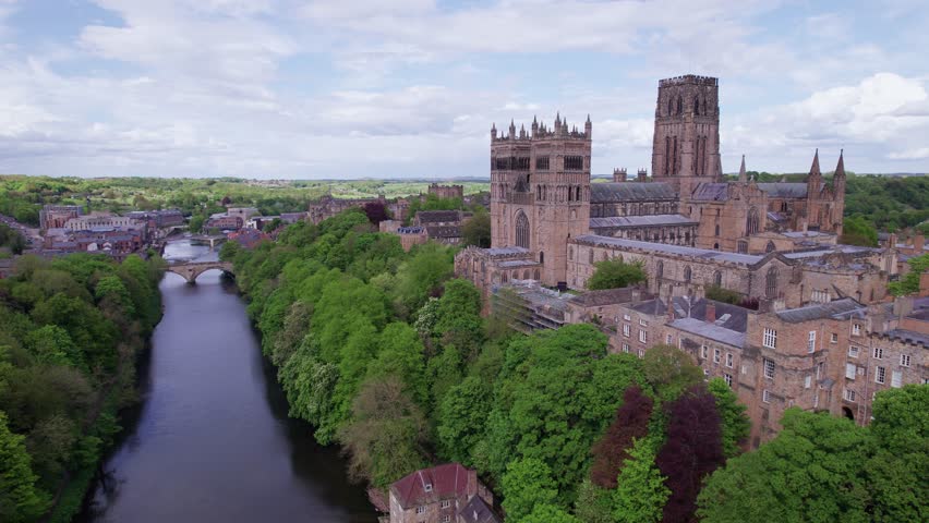 Drone shot flying left above the river Wear showing Durham Cathedral on a sunny day, County Durham, UK