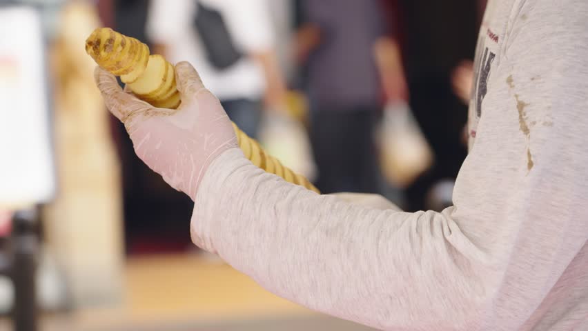 Street vendor preparing Tornado Potato on skewer - popular street food