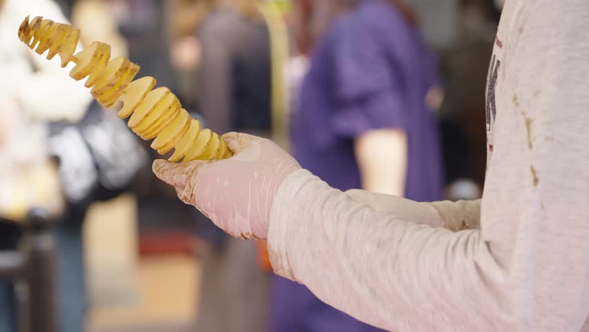 Street vendor preparing Tornado Potato on skewer - popular street food
