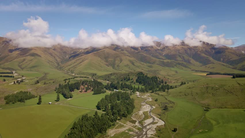 Aerial footage of a winding river coming from a mountain range in the New Zealand countryside