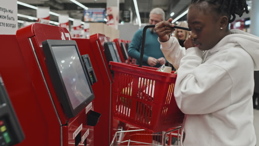 Young Black woman standing at self checkout in supermarket, doing food shopping Royalty-Free Stock Footage #1098785697