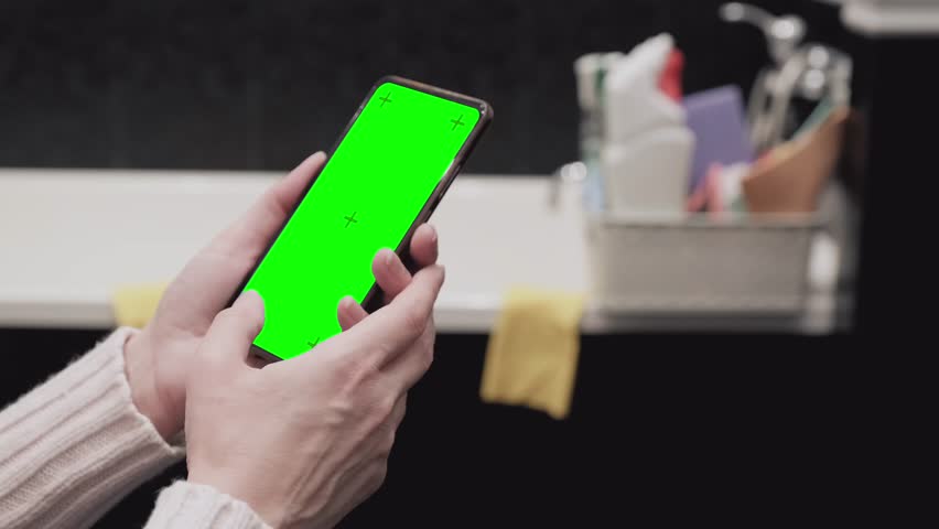Cleaning lady looking at blank smartphone with green screen, mobile application with cleaning service offers, mockup | Shutterstock HD Video #1098789765